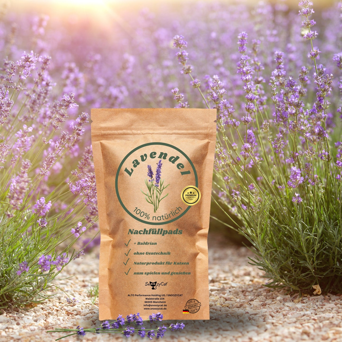 in brauner Kraftpapierbeutel mit der Aufschrift Lavendel 100 % natürlich – Nachfüllpads mit Baldrian steht im Vordergrund eines blühenden Lavendelfeldes. Rechts im Bild ist ein runder Ausschnitt mit Lavendelblüten und einer Baldrianwurzel zu sehen. Die Aufschrift lautet: SNOOZYCAT's Lavendel mit Baldrian – für besondere Wohlfühlmomente. Unten links ist das SNOOZYCAT®-Logo zu sehen.